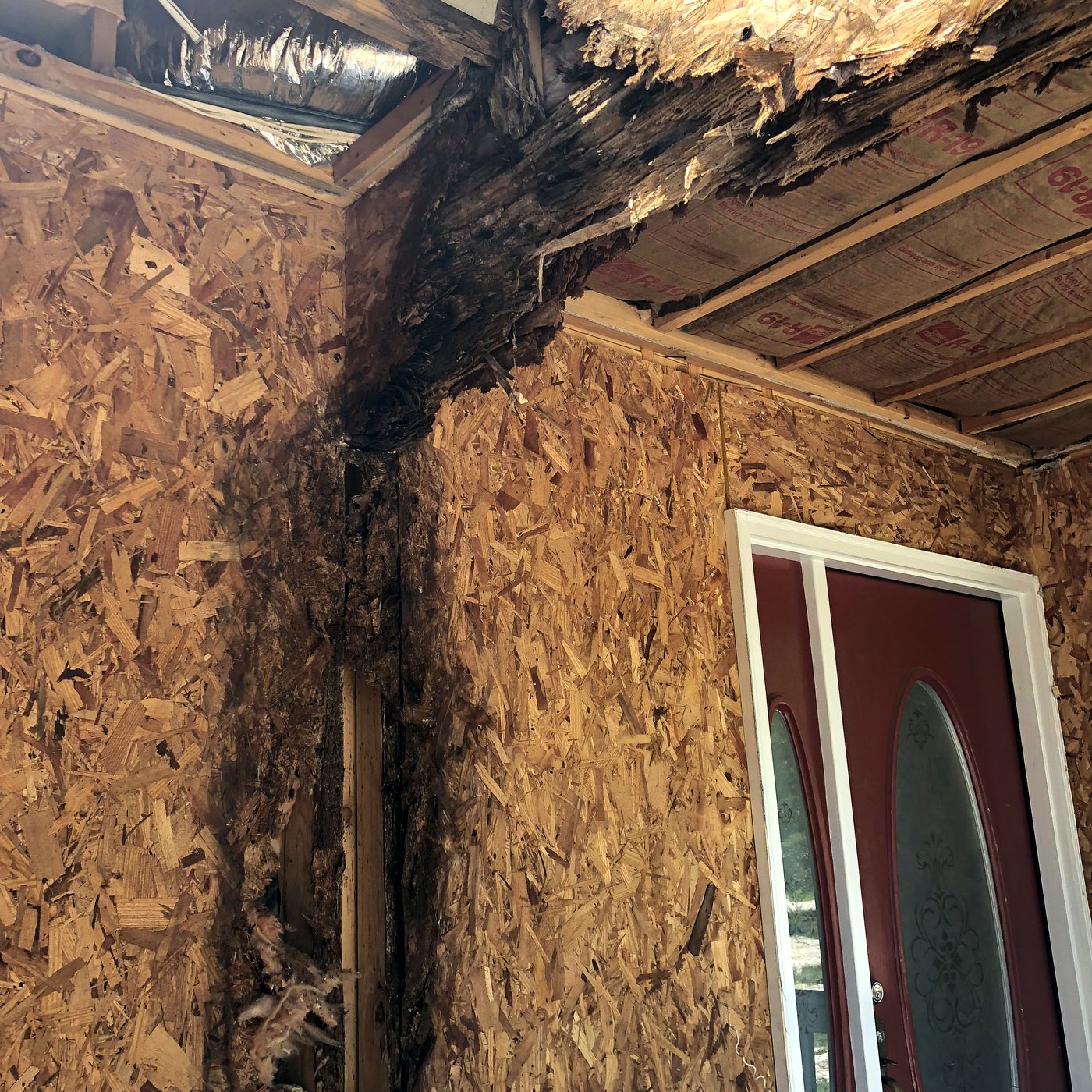 Exterior corner of a coastal Florida home showing rotted soffit and wall framing during demolition